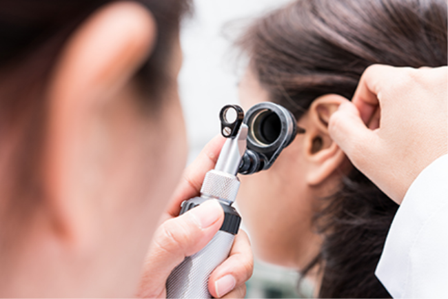 רופא אא"ג בודק לילדה קטנה את האוזניים כדי לאבחן דלקת אוזניים